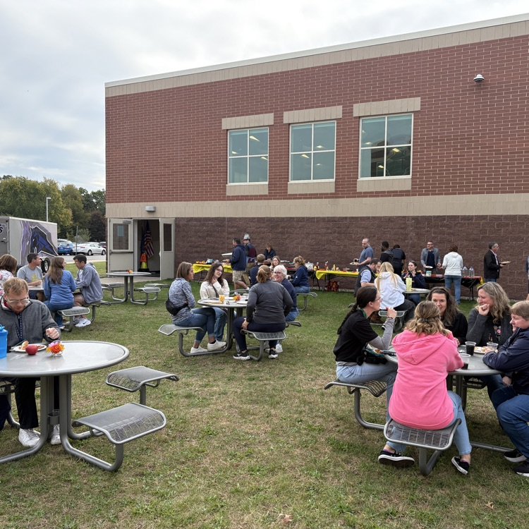 people sitting at tables outside in the grass
