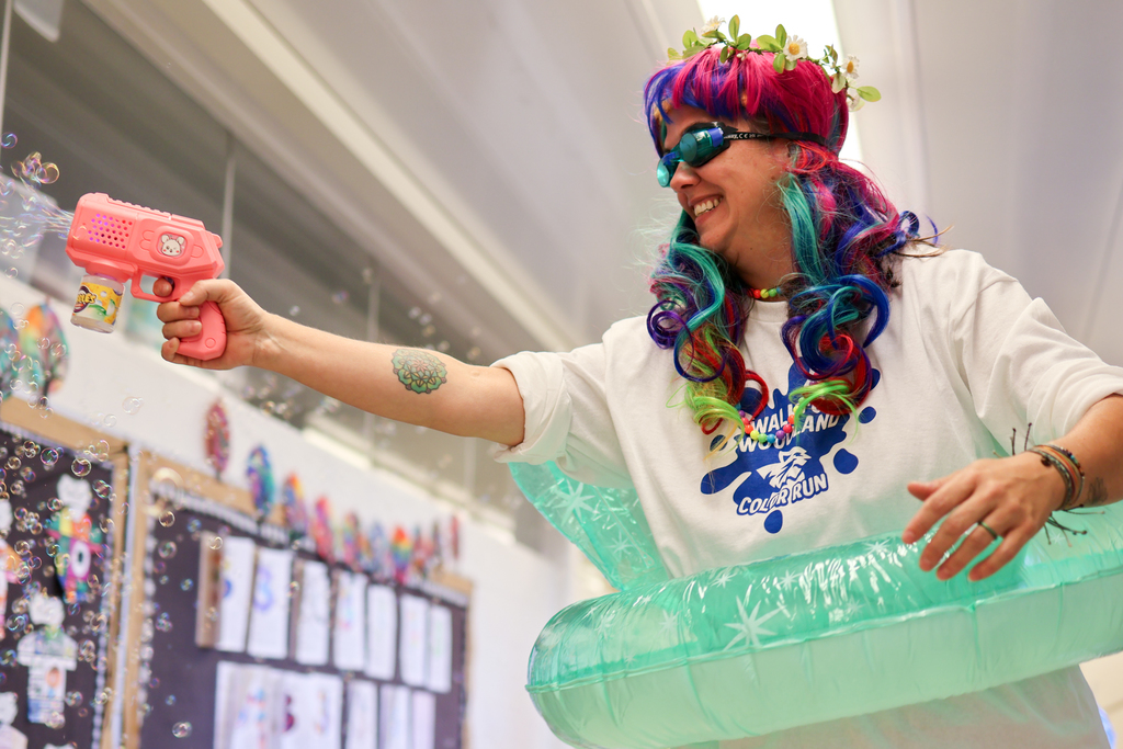 a teacher wearing a colorful wig, swim goggles and a pool floatie in an elementary school