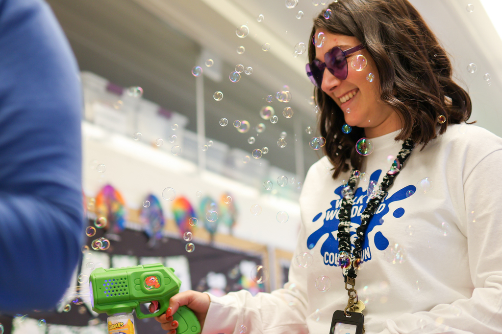 a teacher wearing glasses spraying bubbles 