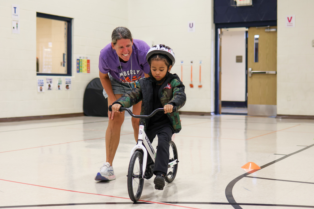 a teacher helping a boy ride a book