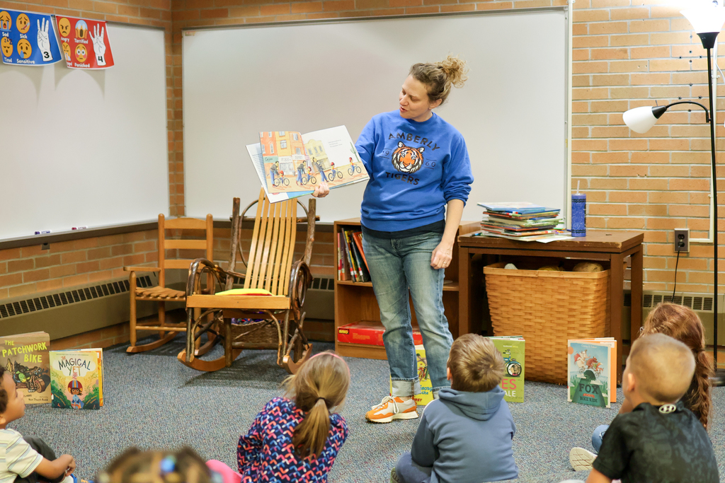 a woman reading a book to children sitting in a library