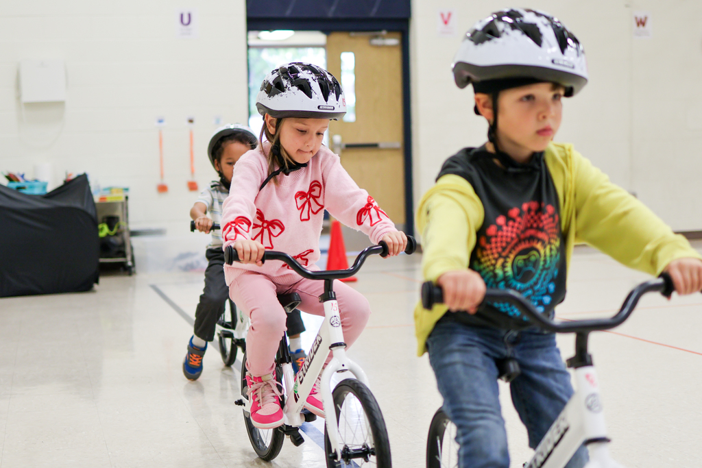 kids riding bikes in a school gym