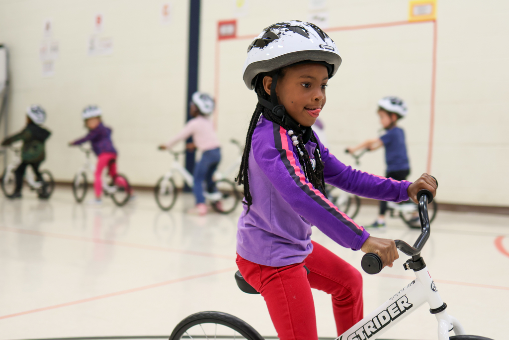 a girl riding a bike inside a school gym