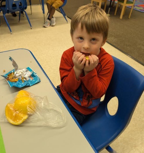 One boy eating a whole orange.