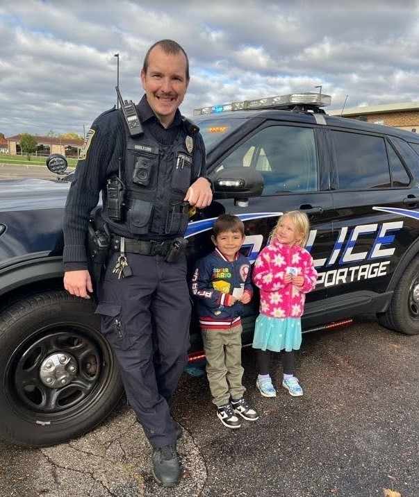 Two kids standing with a police officer.