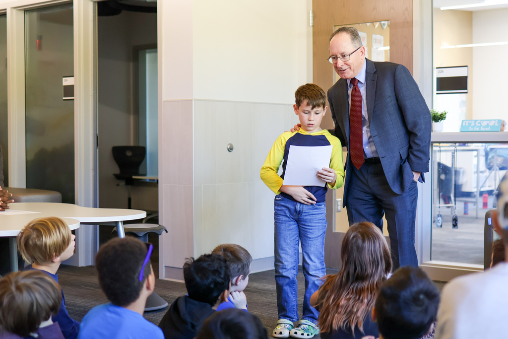 a boy reading a poem standing next toa  man 