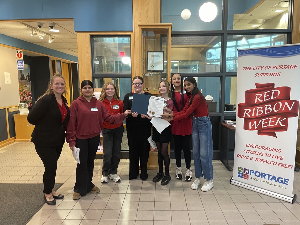 a group of students and a teacher stand in city hall holding a proclamation for red ribbon week