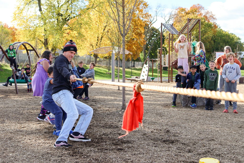 a teacher and students playing tug-of-war outside
