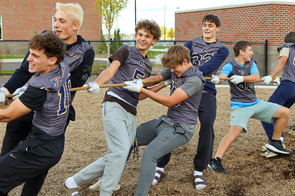 high school football players playing tug-of-war outside on a playground