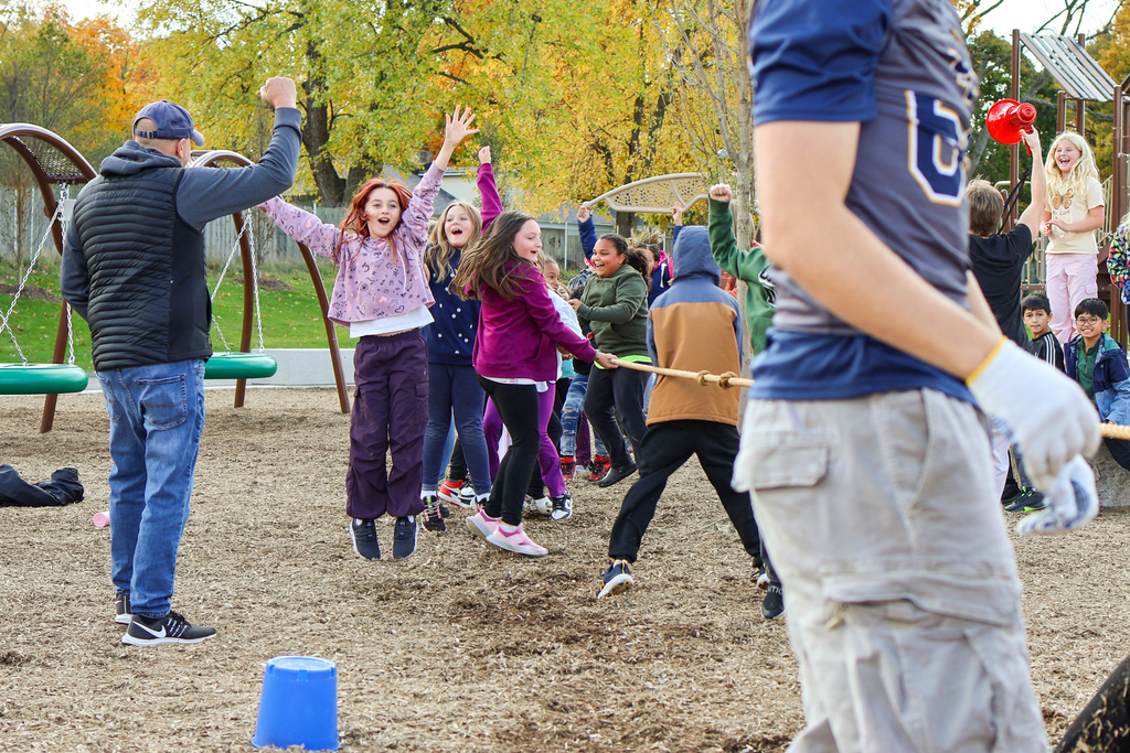 a girl jumps and cheers outside on a playground