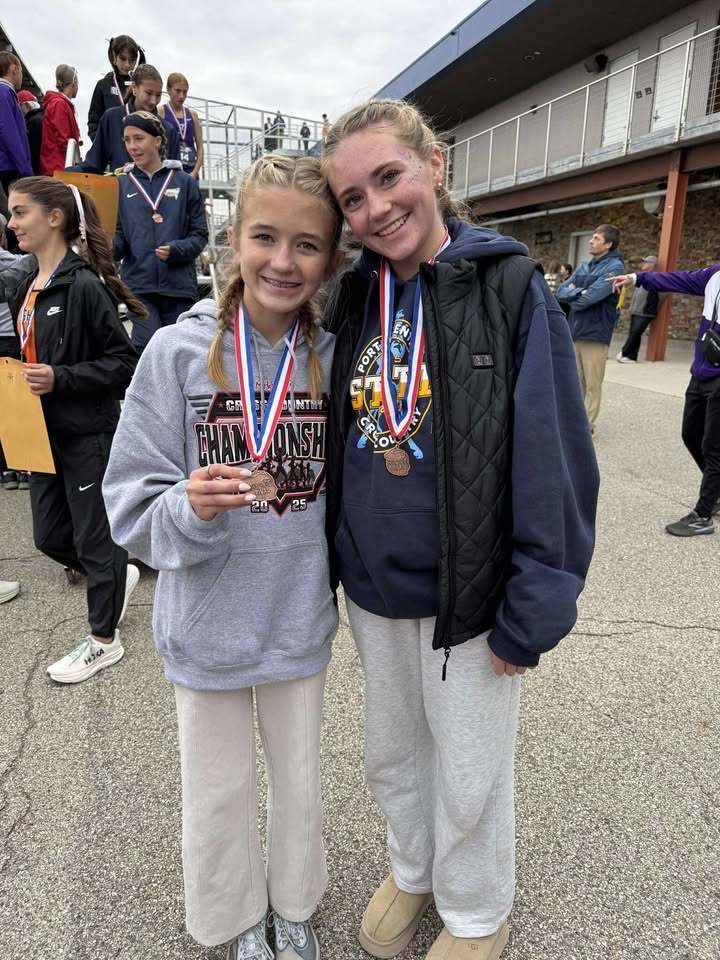 two girls pose for a photo with medals at a track meet