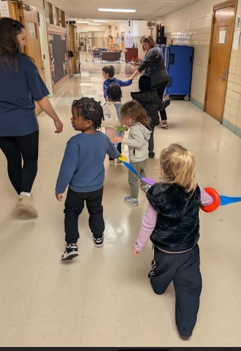Students walking in a line together holding a rope.
