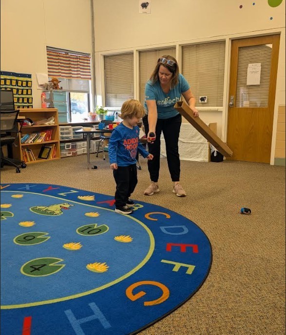 Student trying to get the small car on the carpet in the classroom.