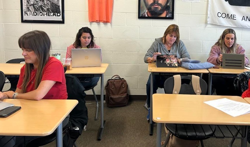 Four teachers working on a computer. 