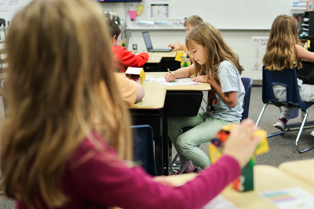 students coloring at desks in a classroom