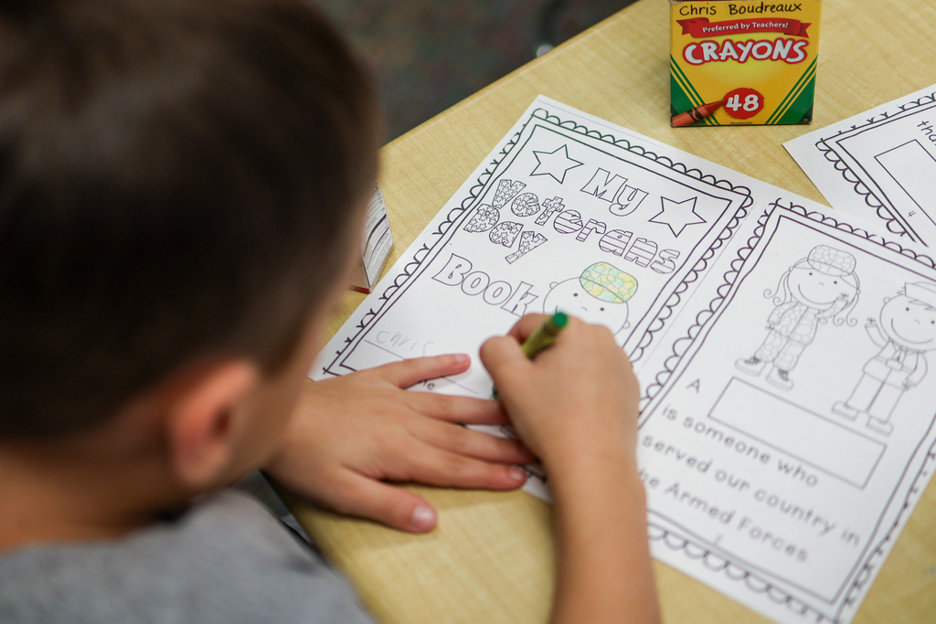 a student colors pages that have veterans themed images