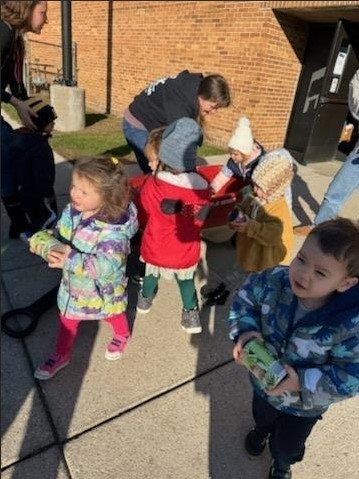Toddlers carrying food to the trunk of the car.
