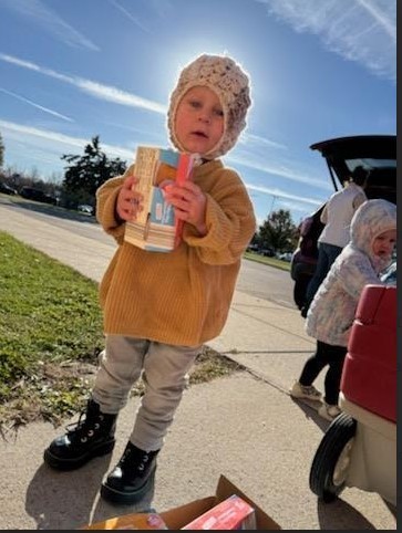 A little boy hodling food with a hat on.