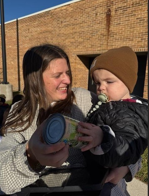 A teacher and a child carrying a can together. 