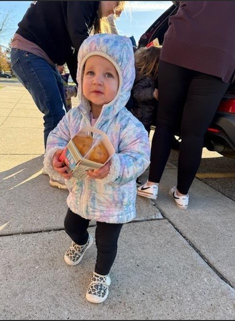 A little girl carrying peaches.
