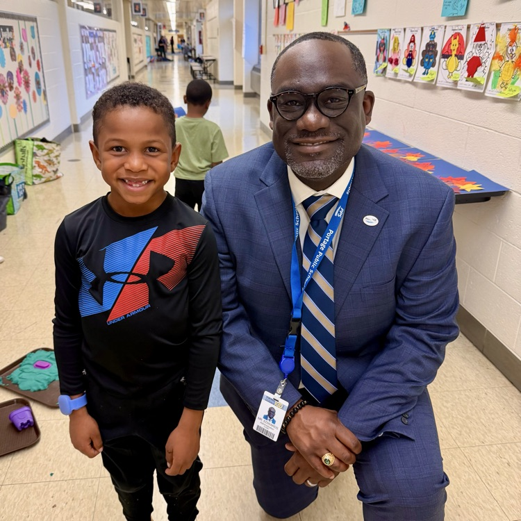 a man and boy pose for a photo in a school hallway