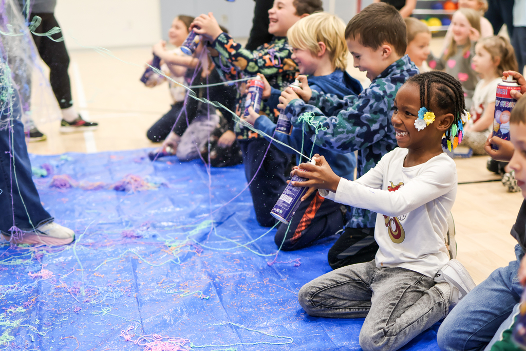 students smiling while spraying silly string in a school gym