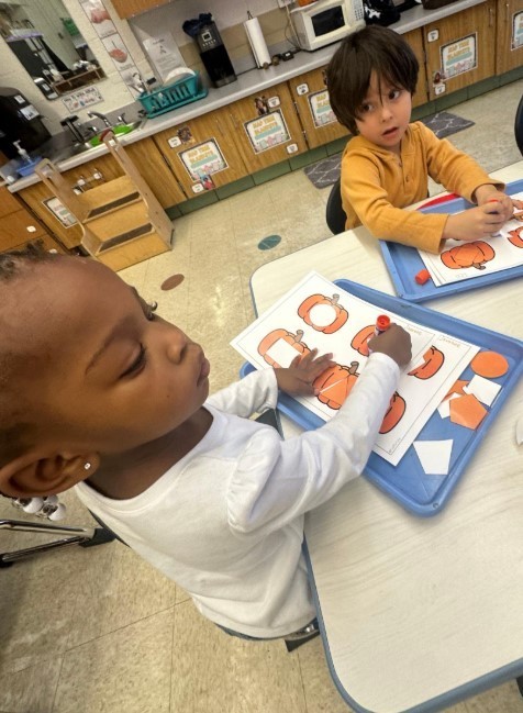 A little girl and boy working on pumpkins together.