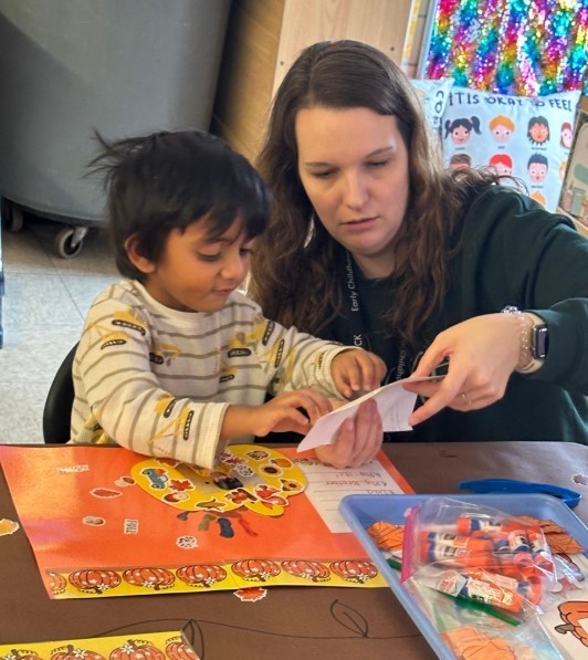 An adult helping a student with a paper activity.