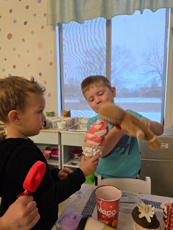 Two male students playing in the dramatic play area together.
