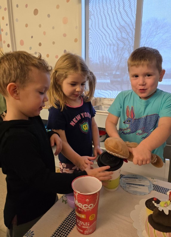 Three preschool students in the dramatic play area.
