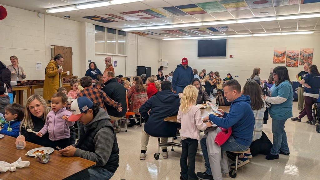 A view of the cafeteria where our families are enjoying pizza, cookies and each other.