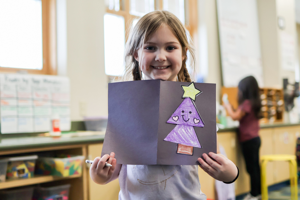 a little girl holding her card smiles for the camera