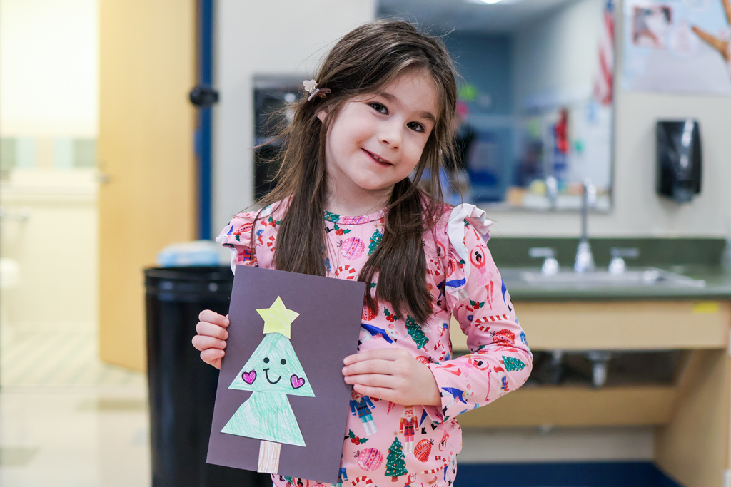 a little girl holding her card smiles for the camera