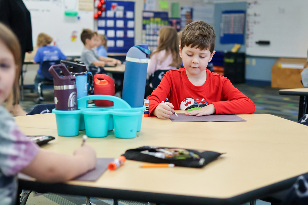 students working on cards at a desk in a classroom