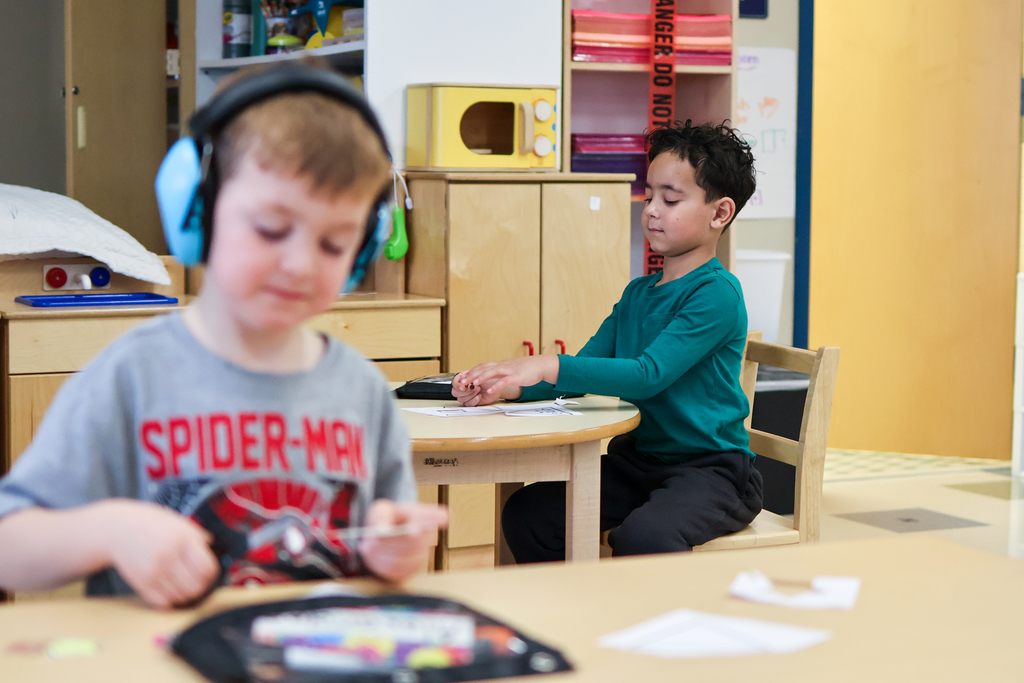 two boys working on crafts at their desks in a classroom