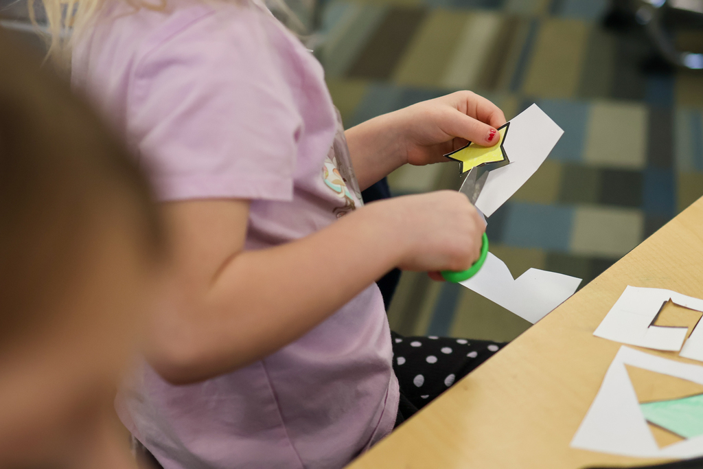 a girl cutting paper at a school desk