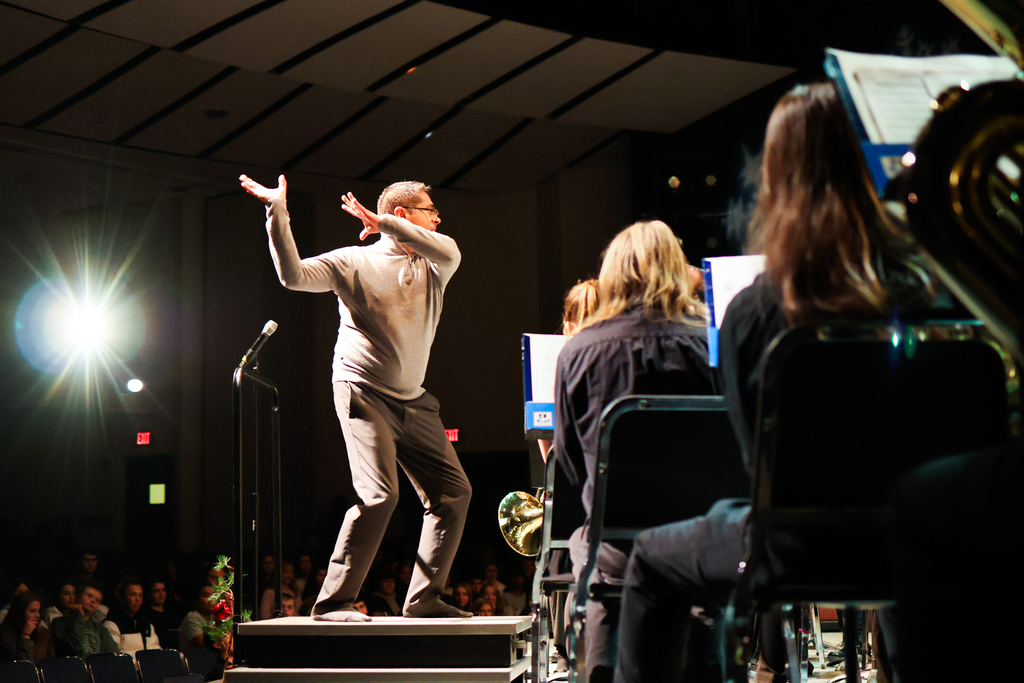 a man directing a high school band on stage