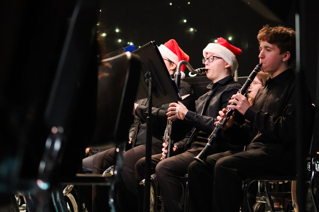 students in santa hats playing musical instruments on stage