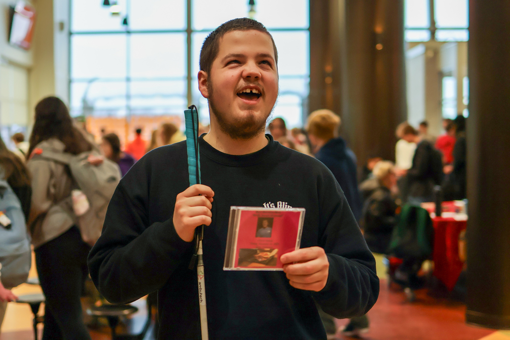 a visually impaired student smiles for a photo holding a CD