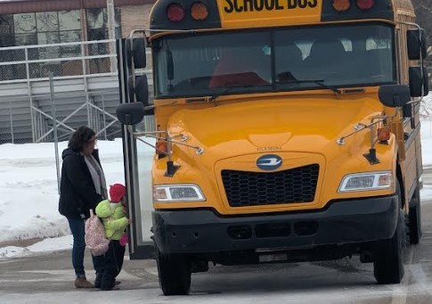 Student and teacher entering a bus.