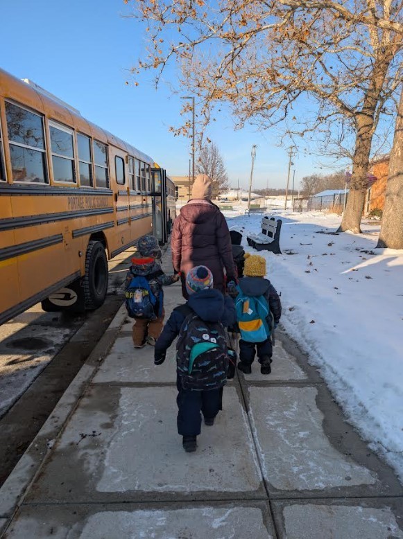 Students walking to the bus on the sidewalk.
