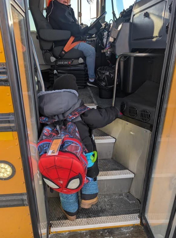 Student walking up the ramp of a bus.