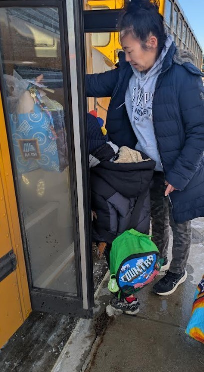 Teacher helping a student get on the bus.
