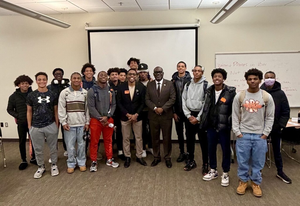 a group of high school boys pose for a photo with two men in a school