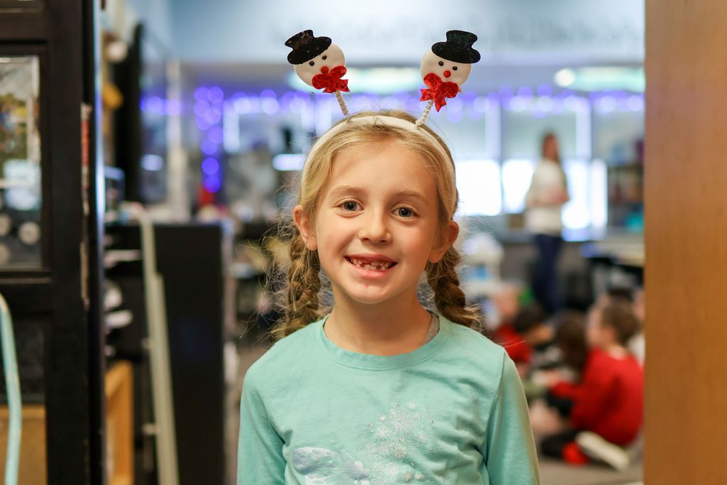 a girl wearing a holiday headband smiling for a photo