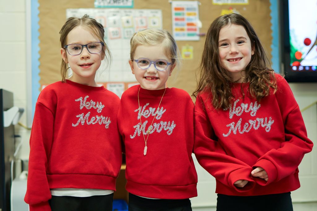 three girls in matching sweatshirts pose for a photo