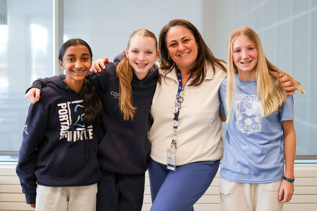 a woman and three girls smile for a photo