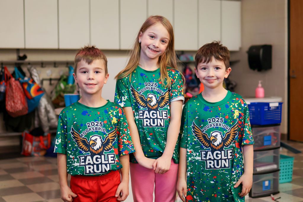 three students wearing matching shirts pose for a photo