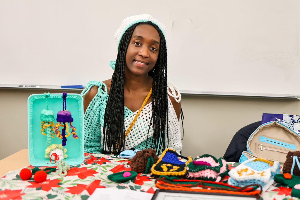 a girl posing for a photo next to her crochet creations