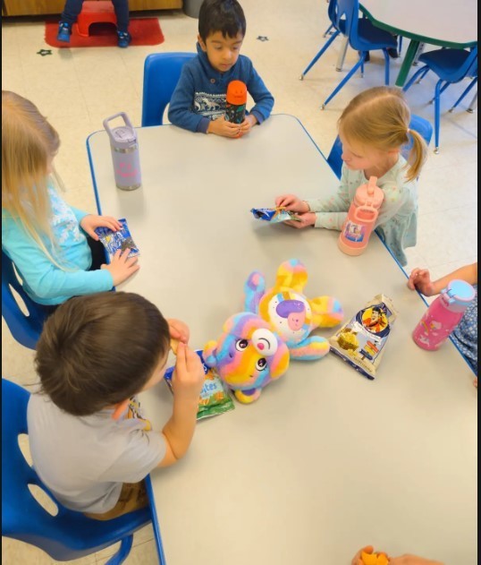 Two preschool girls and two preschool boys eating popcorn.